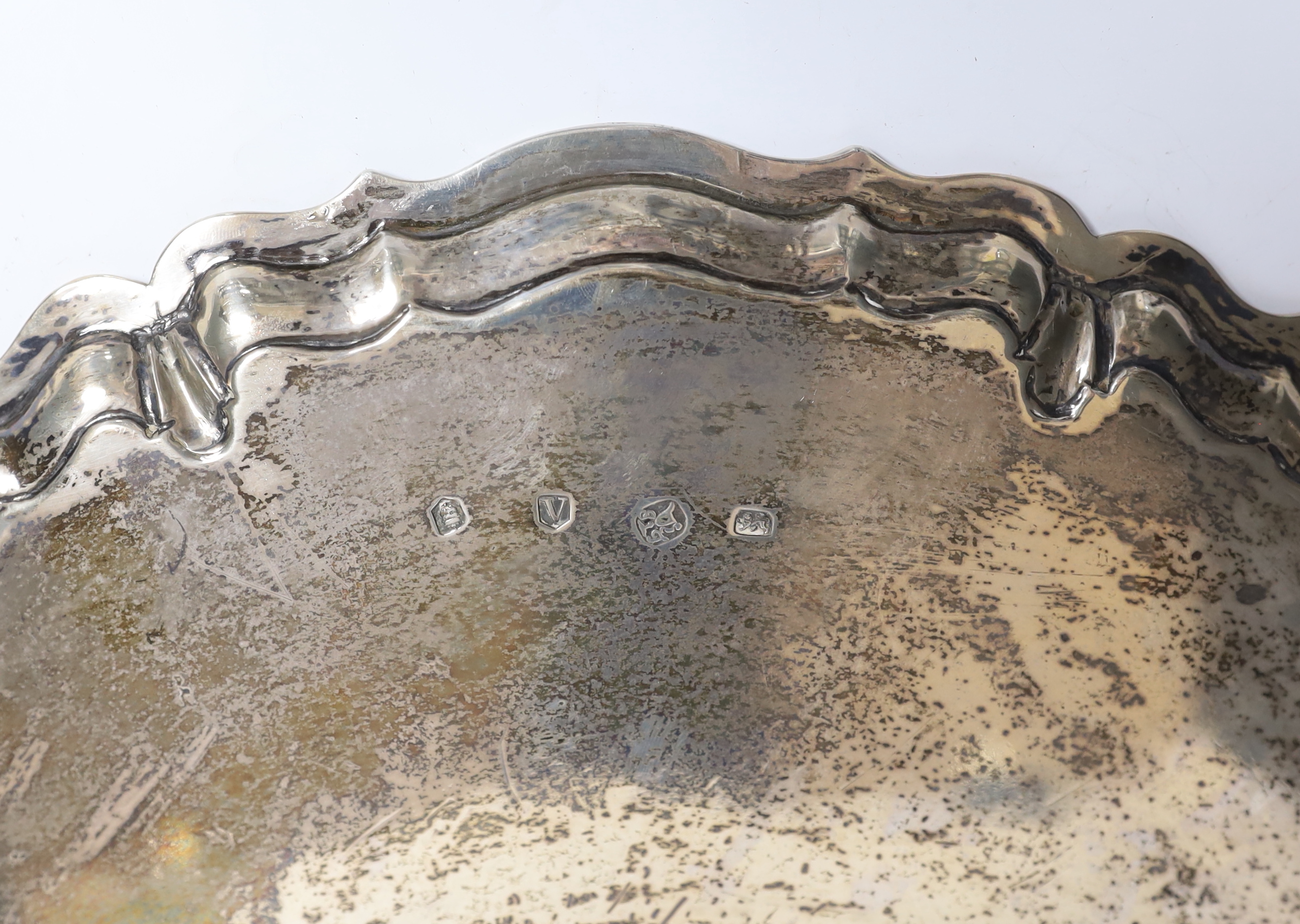 A large George II silver shaped circular salver, with pie crust border and engraved armorial, on four scroll feet, by John Tuite, London, 1735, diameter 36.6cm, 43.1oz.